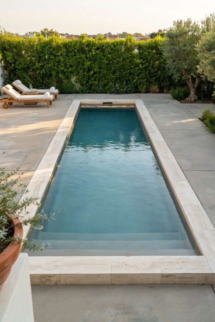 Luxury in-ground concrete swimming pool seamlessly integrated into a professionally landscaped backyard with stone coping.